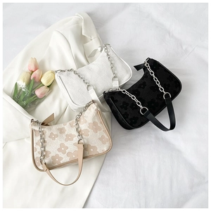 Three pleated shoulder bags in white, black and floral patterns with metal chain straps