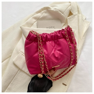 Détail d'un sac fuchsia matelassé avec bandoulière chaîne dorée sur blazer