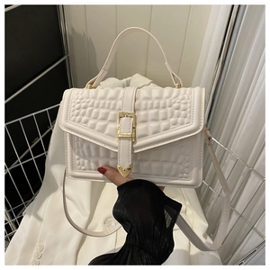 Detail of cream white faux leather handbag with crocodile pattern and golden buckle
