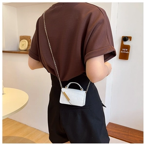 Detail of white crocodile embossed mini crossbody bag with gold chain on model shoulder