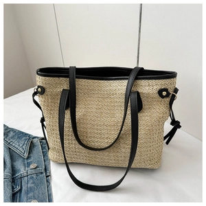 Detail of handwoven straw tote bag featuring black leather trim and drawstring accents