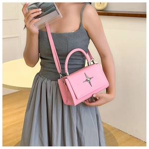 Detailed macro view of pink pebbled leather handbag with silver star buckle and woven handle