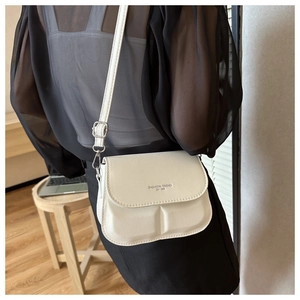 Detail view of cream PU leather crossbody bag featuring fashion trend text and adjustable strap
