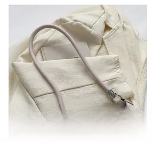 Close-up of pink round handle and blue denim fabric on a minimalist shoulder bag