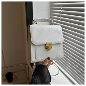 Detail of a white structured mini backpack with gold metal clasp and top handle