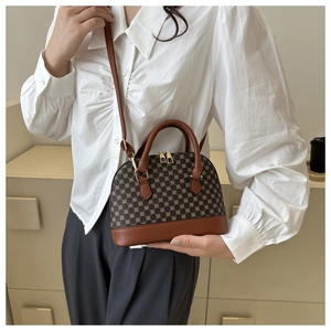 Detail van een vintage bruine schelpvormige crossbodytas gedragen door een model in stijl