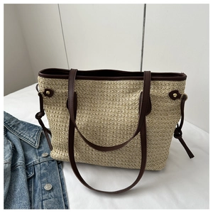 Top view of woven straw tote bag with brown leather handles and side knot details