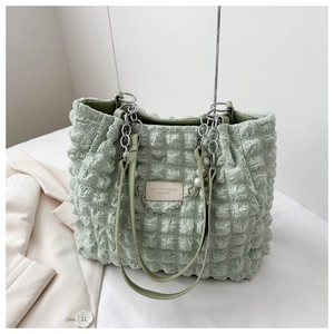 Macro view of green bubble textured tote bag with silver chain and pearl pendant detail