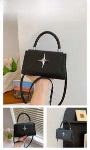 Detail of black pebbled leather crossbody bag with silver star emblem and woven handle