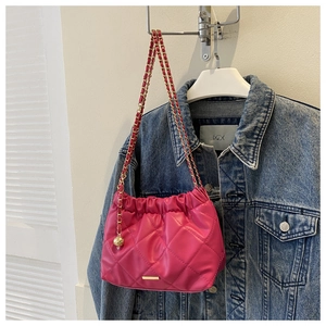 Détail du sac seau matelassé rose vif avec bandoulière en chaîne dorée et perle
