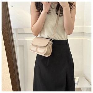 Detail of a beige crossbody square bag featuring a structured panel design and metal buckle