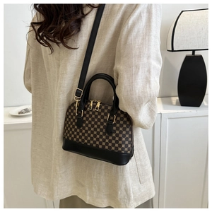 Detailopname van retro schelpvormige tas met geometrische print en gouden hardware