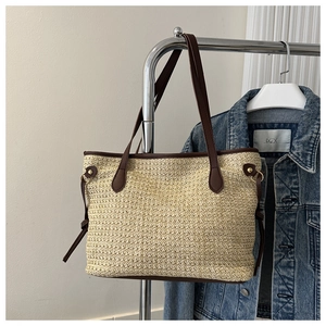 Detail of hand-woven straw tote bag with brown leather handles and decorative metal buckle