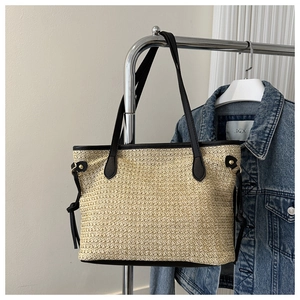 Detail view of straw tote bag with black leather straps and drawstring decorative accents