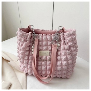 Detail of light pink bubble textured tote bag with pearl and floral charms and chain strap