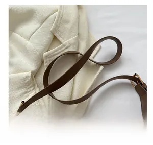 Detail of wide brown leather shoulder strap with gold buckle on a stylish tote bag