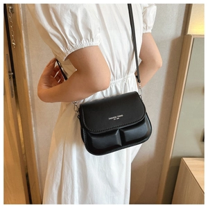 Close-up of black crossbody bag featuring padded quilted texture and fashion slogan