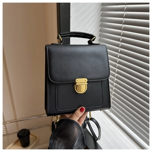 Detail of a vintage black PU leather handbag featuring a golden rectangular metal clasp lock