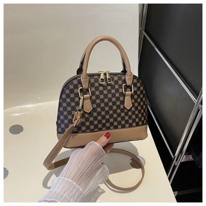 Detail of vintage shell bag with dark brown monogram pattern and khaki leather handle