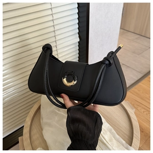 Close-up of black leather underarm bag featuring a circular metal buckle and knotted strap