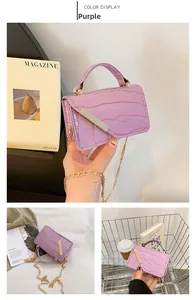 Detail of purple croc-effect crossbody bag with gold chain and metal trim accents