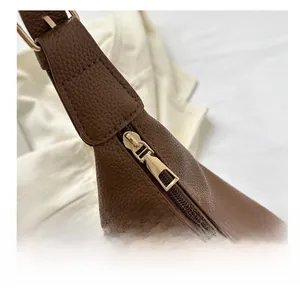Detail of dark brown lychee leather bag with golden metal zipper and smooth stitching