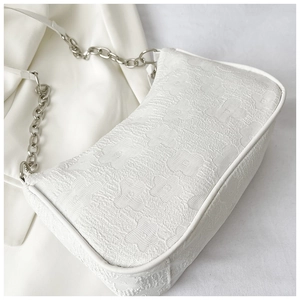 Detail of white floral jacquard fabric and silver metal chain strap on shoulder bag