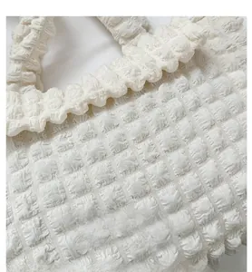 Detailed close-up of white bubble textured fabric and ruffled handle of the shoulder bag