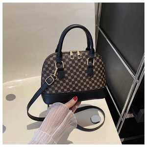Detail of vintage shell bag with gold geometric patterns and black leather handle