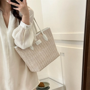 Large beige straw woven tote bag with white leather handles and stylish trim for summer