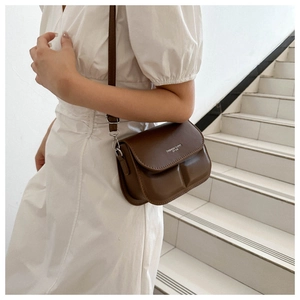 Detail of dark brown crossbody bag with embossed texture and adjustable shoulder strap