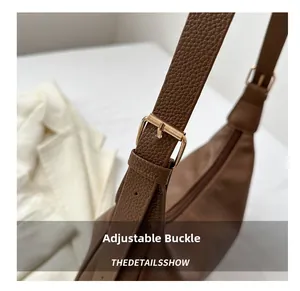 Detail shot of the adjustable metal buckle and stitching on the dark brown leather handbag