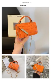 Detail of orange crocodile pattern mini bag with gold chain and metal bar accent