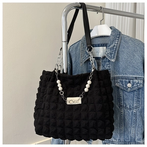 Detail of black puff texture tote bag with pearl chain and silver metal accents
