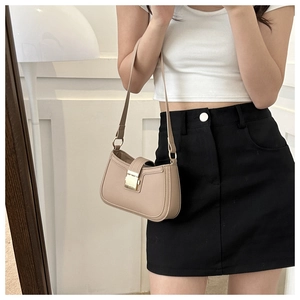 Détail d'un sac à bandoulière en cuir beige avec boucle métallique et design minimaliste chic