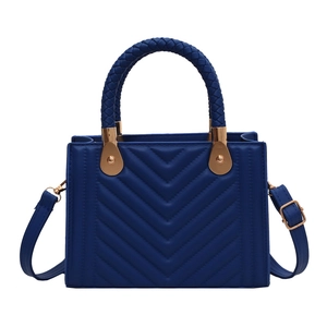 Navy blue V-quilted handbag with woven handles and golden hardware in a 45-degree view