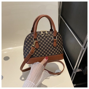 Detail of retro shell handbag showing brown geometric pattern and caramel leather straps