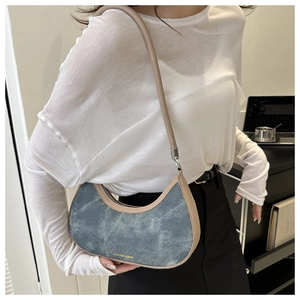 Detailed macro of vintage denim crescent bag with beige leather trim and gold fashion logo