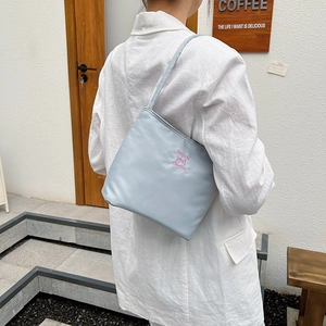 Light blue nylon shoulder bag with pink letter embroidery shown on model shoulder