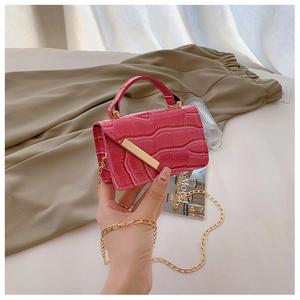 Close-up of pink faux crocodile leather texture and golden metal bar on mini square bag