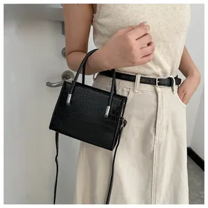 Detail of a black faux crocodile texture handbag with silver metal hardware and slim handle