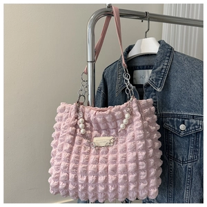Detailed view of pink bubble textured tote bag with decorative pearl and metal chain strap