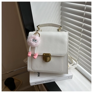 Detailed shot of a white PU leather mini backpack with gold buckle and plush ball charm