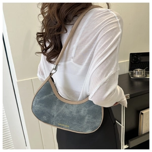 Crescent shoulder bag in blue denim with brown leather trim shown on a model