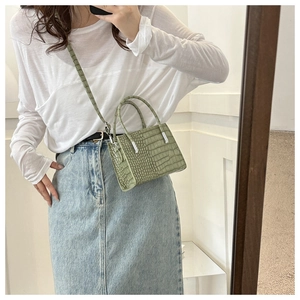 Detailed macro view of green crocodile embossed texture on a chic trapezoid crossbody bag