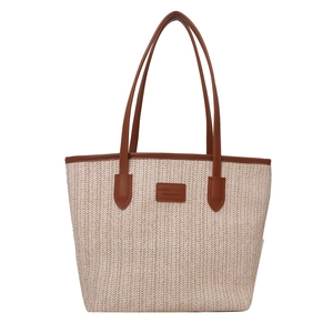 Large straw tote bag with brown leather handles and center patch on white background