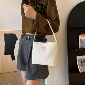 Minimalist white nylon shoulder bag with pink embroidery lettering in a daily scene