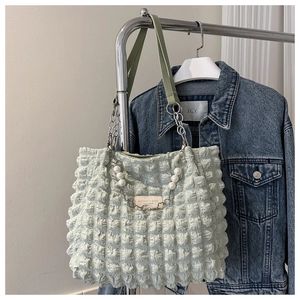 Detail of light green bubble texture shoulder bag with pearl chain and fashion leather tag
