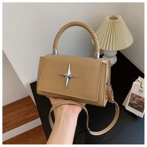 Detail of lychee pattern leather handbag featuring a silver star ornament and woven handle
