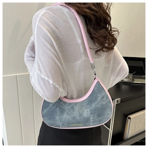 Detail of blue denim underarm bag with pink leather handle shown on model